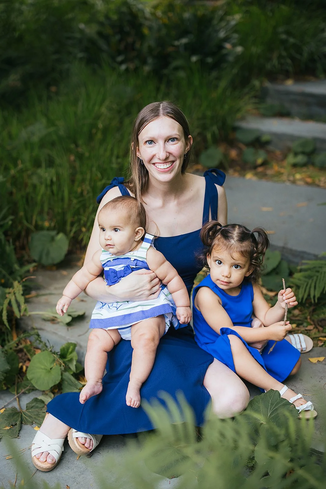 Mom in Blue Dress With Two Daughters Sitting Among Leaves at Duke Gardens