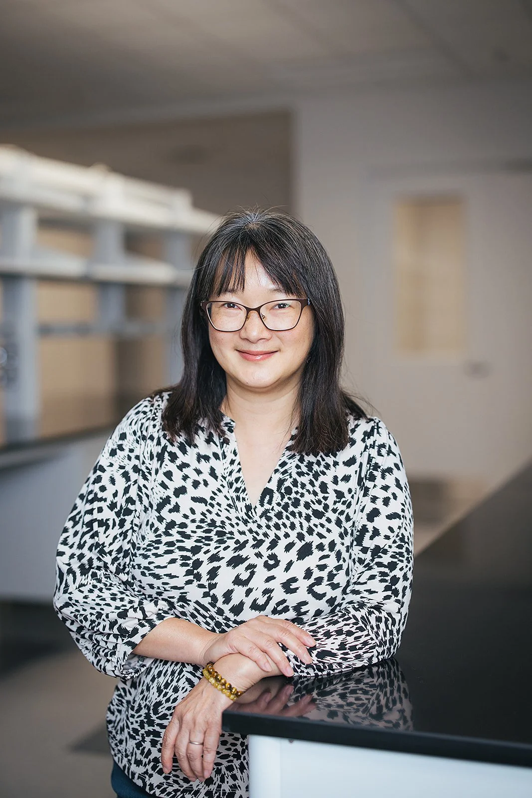 WomanSmilingHeadshotLeaningOnTable