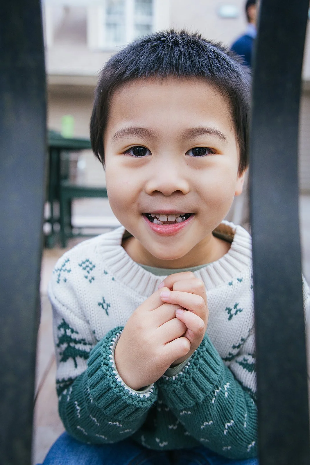 Young boy in green and white sweater smiling during family portrait session