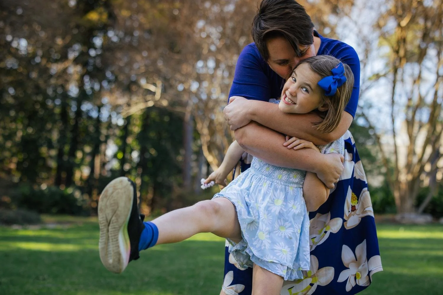 Dad lifting his older daughter off the ground as both laugh together during a Duke Gardens family session in Durham NC