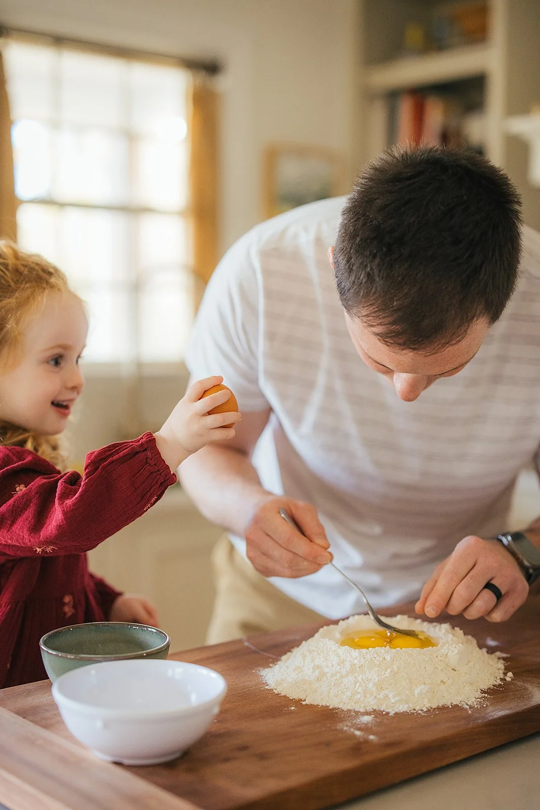 Dad and toddler daughter make pasta dough together at kitchen island during Durham lifestyle family photography session