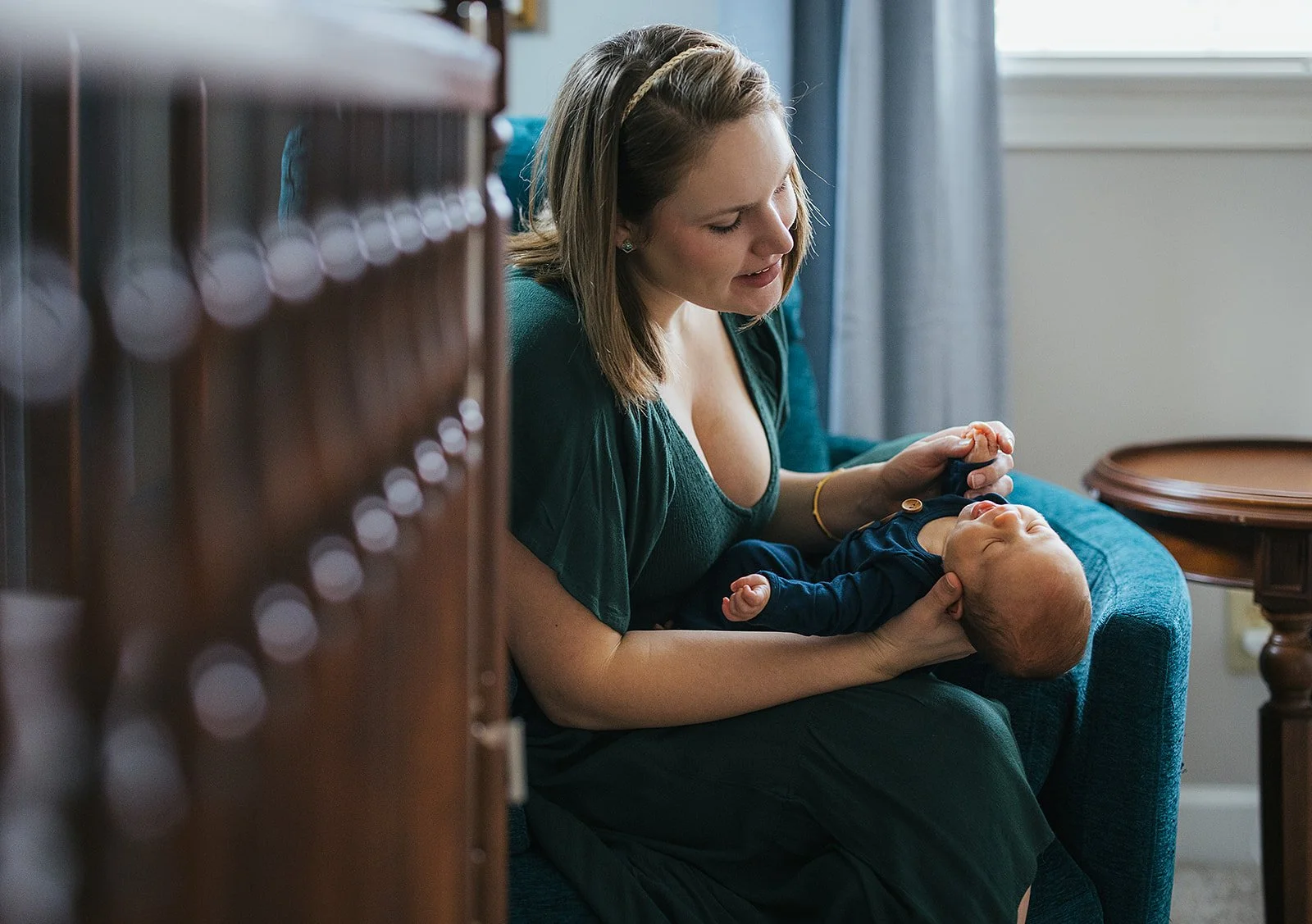 Mother plays with baby in nursery at a newborn session in Durham, NC