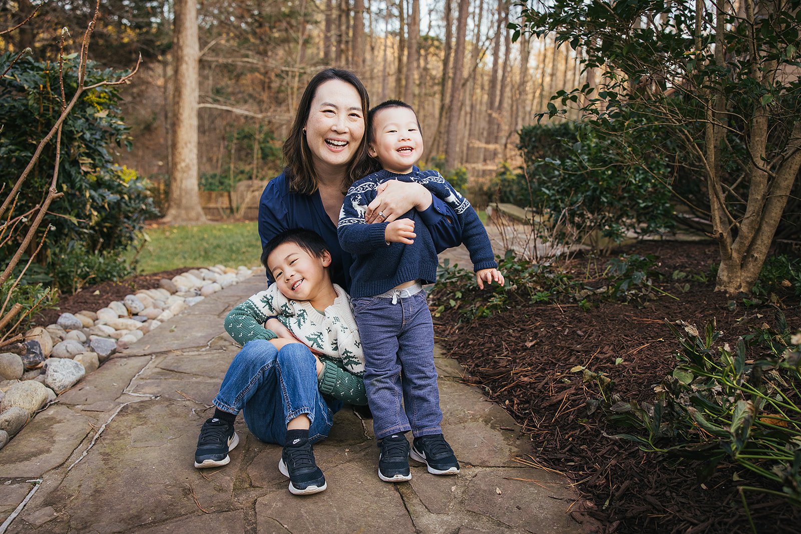 Mom laughing with two young boys outside during family portrait session