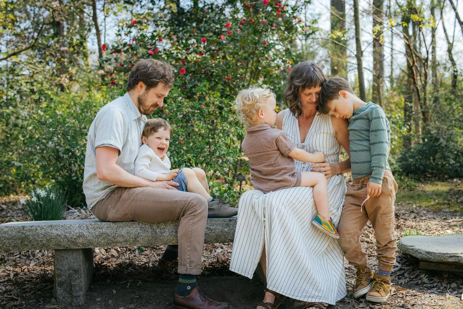 family enjoying a joyful and cuddly moment during a photoshoot at duke gardens in Durham, NC