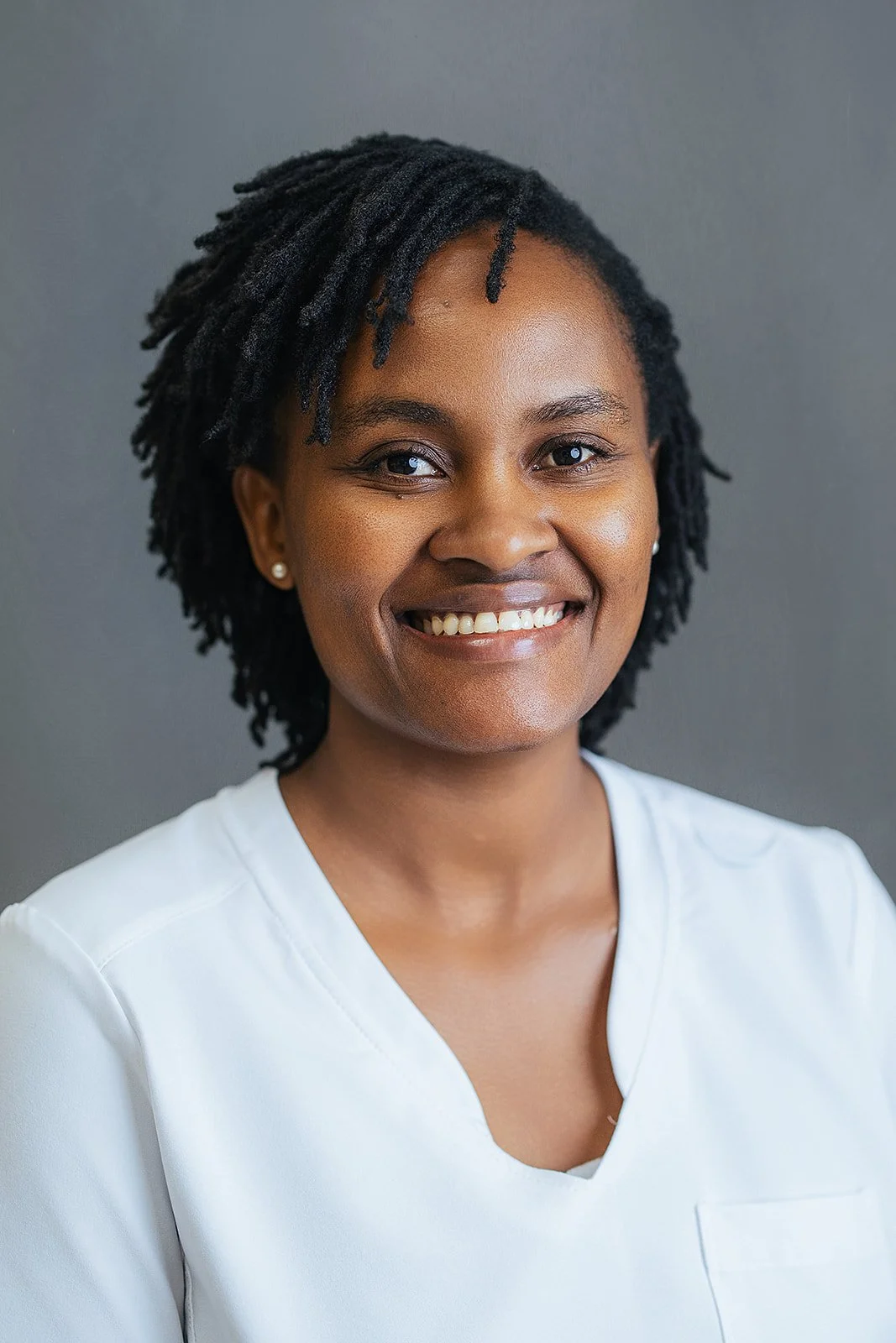 Durham Tech nursing student with short locs, warm bright smile in white scrubs, professional headshot by Fifty Two Hundred Photography Durham NC