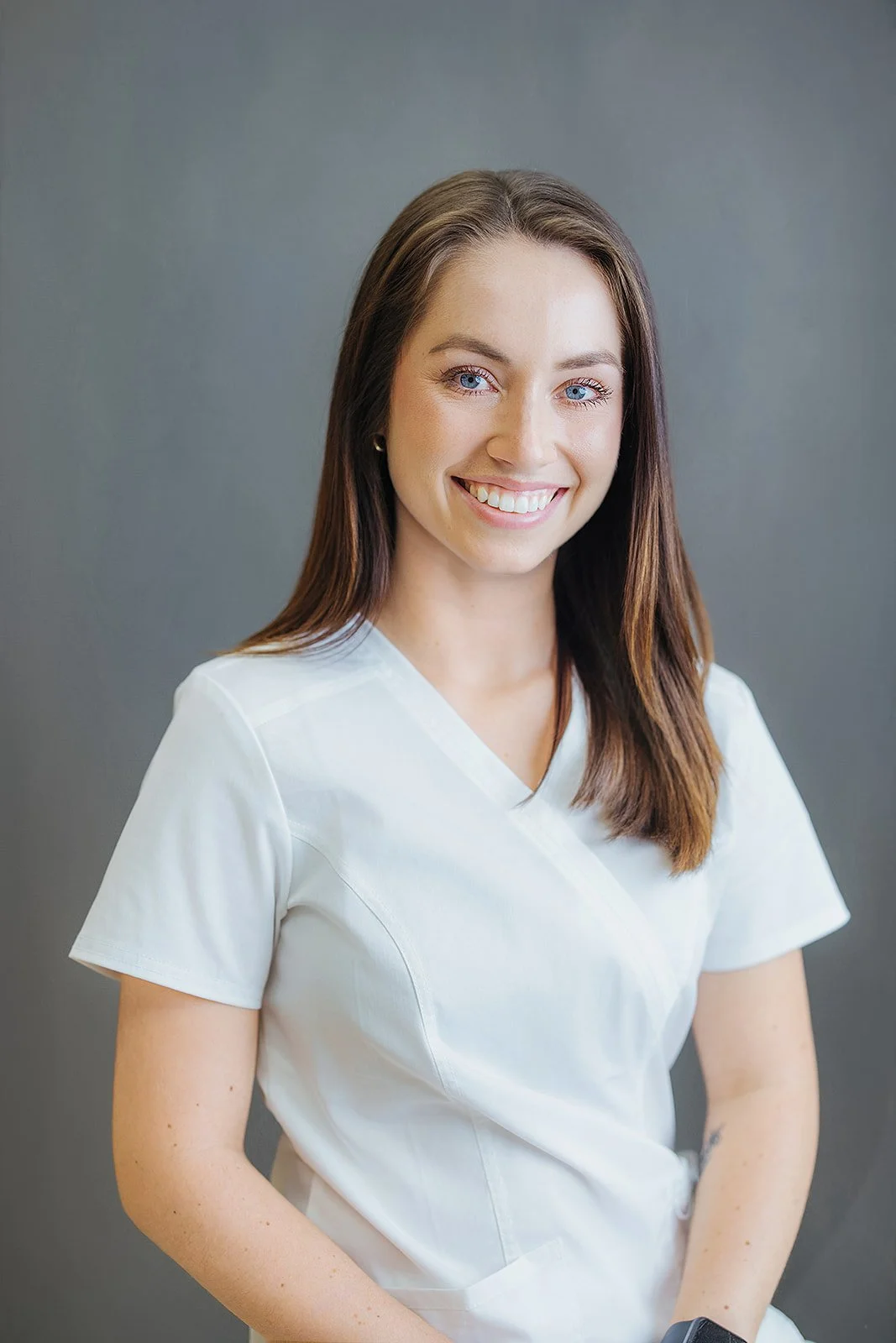 Durham Tech nursing student with long brown hair, warm smile in white scrubs, professional nursing headshot by Fifty Two Hundred Photography Durham NC