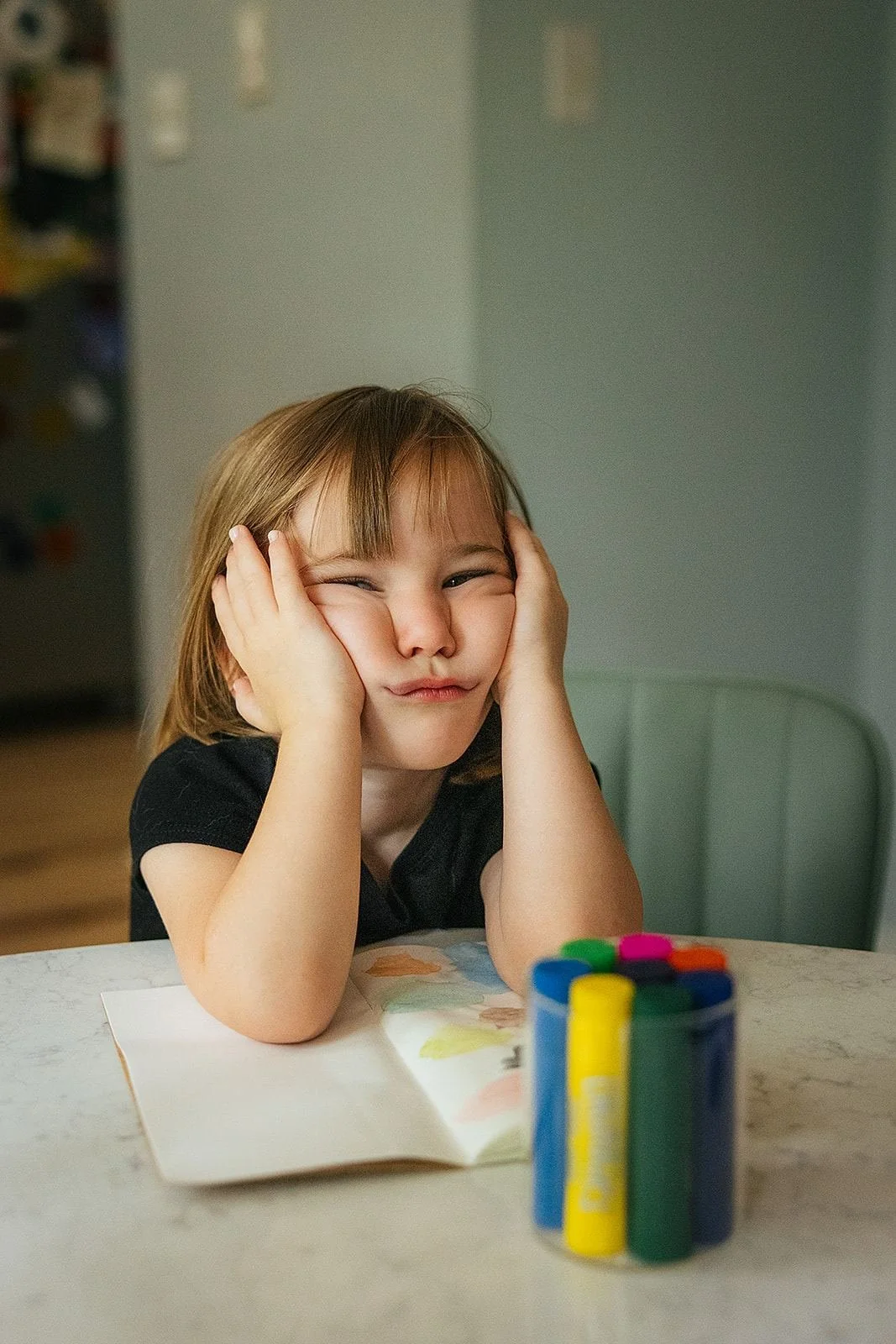 Young Girl Making Funny Face at Kitchen Table