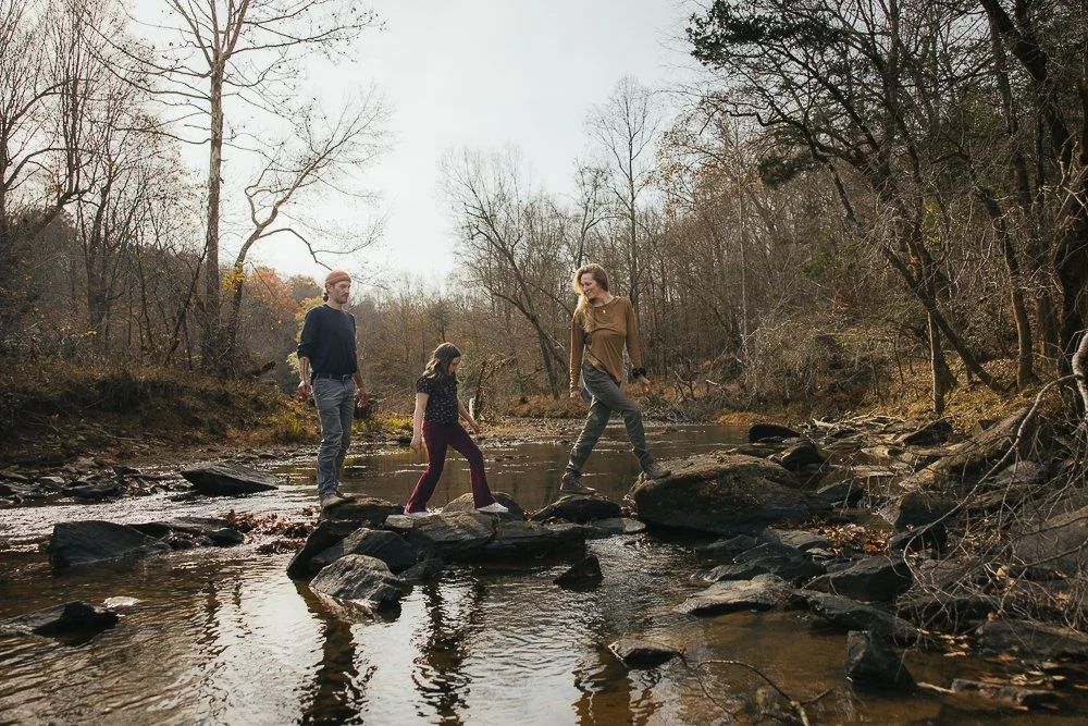 Couple and Young Girl Walking Along Rocks In Stream
