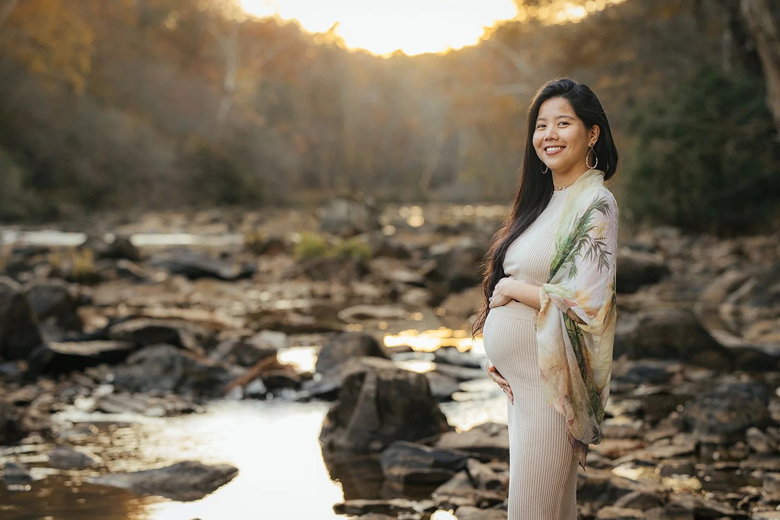 A pregnant woman holds her belly on the Eno River for maternity photography