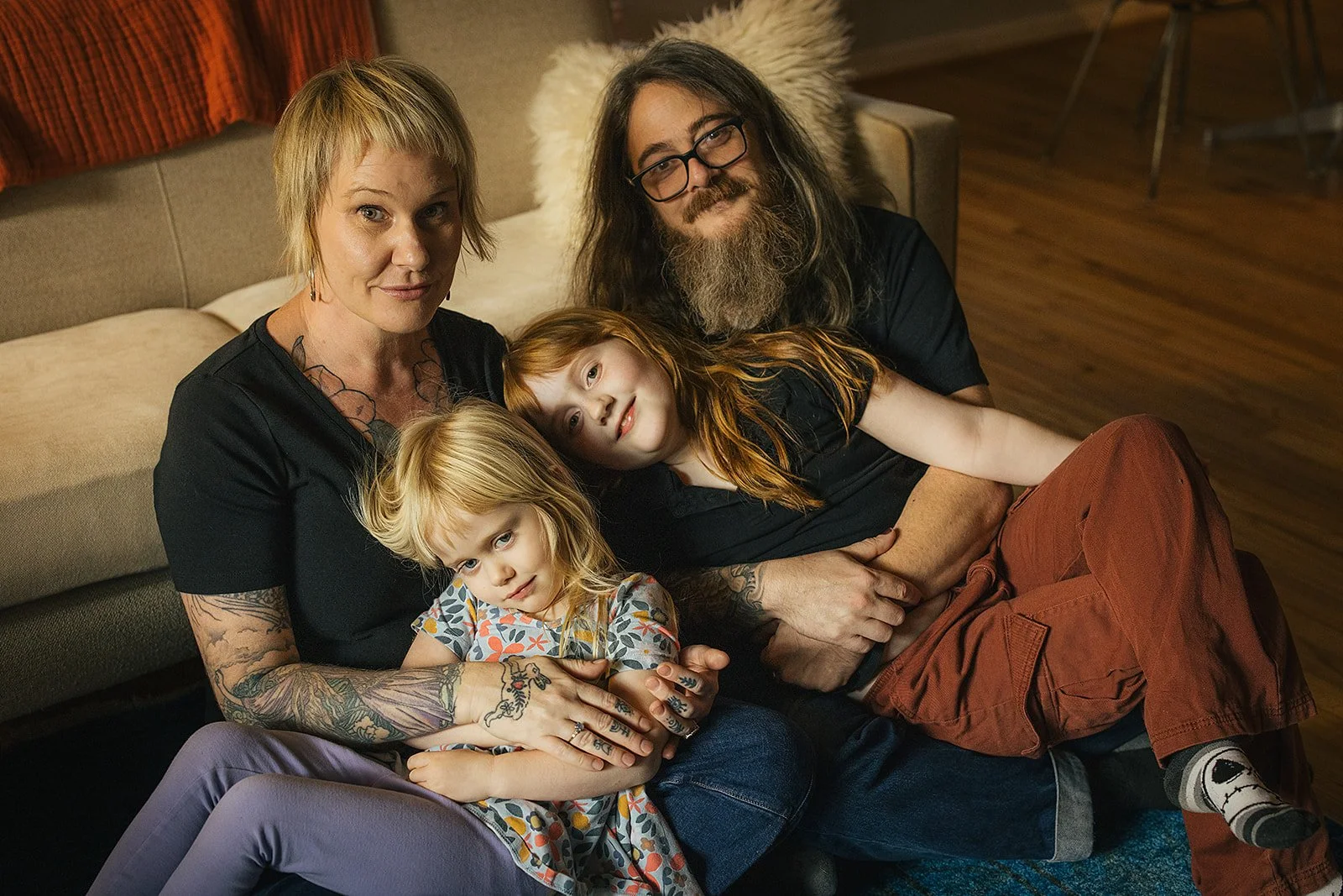Mom, Dad, and Young Girls Sitting Together on Living Room Floor