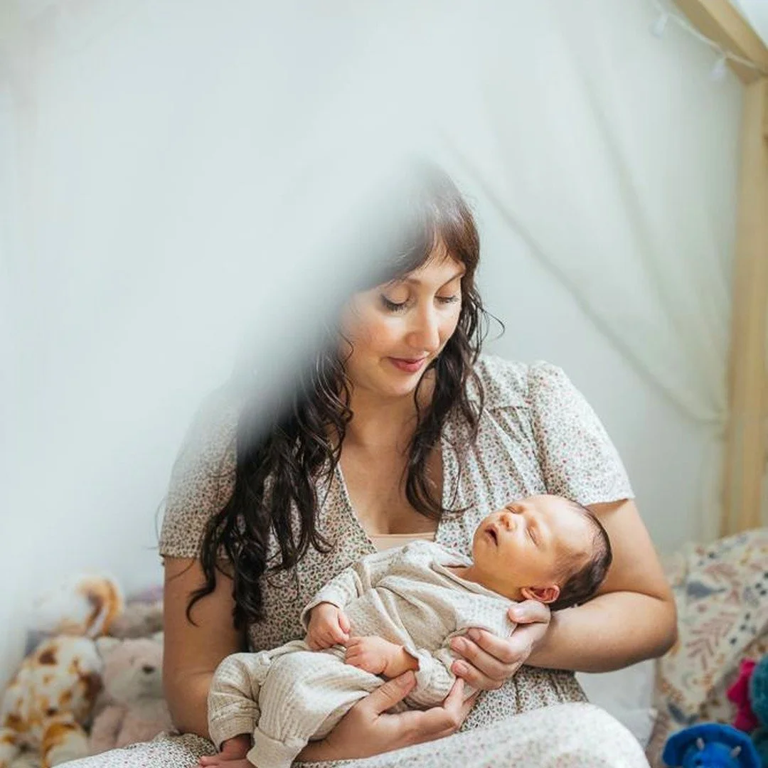 Mother lovingly holds her newborn during an at home newborn photo session in Durham, NC