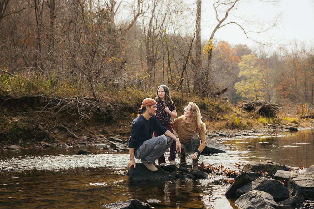 Couple and Young Girl Walking Through Creek Outside