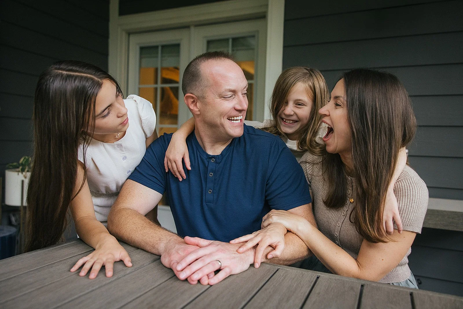 Family fo four laughing on patio during in-home photography session