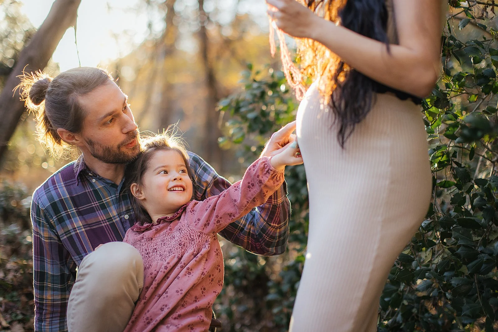 A child pointing to her mother during a maternity photoshoot at the Eno River in Durham, North Carolina