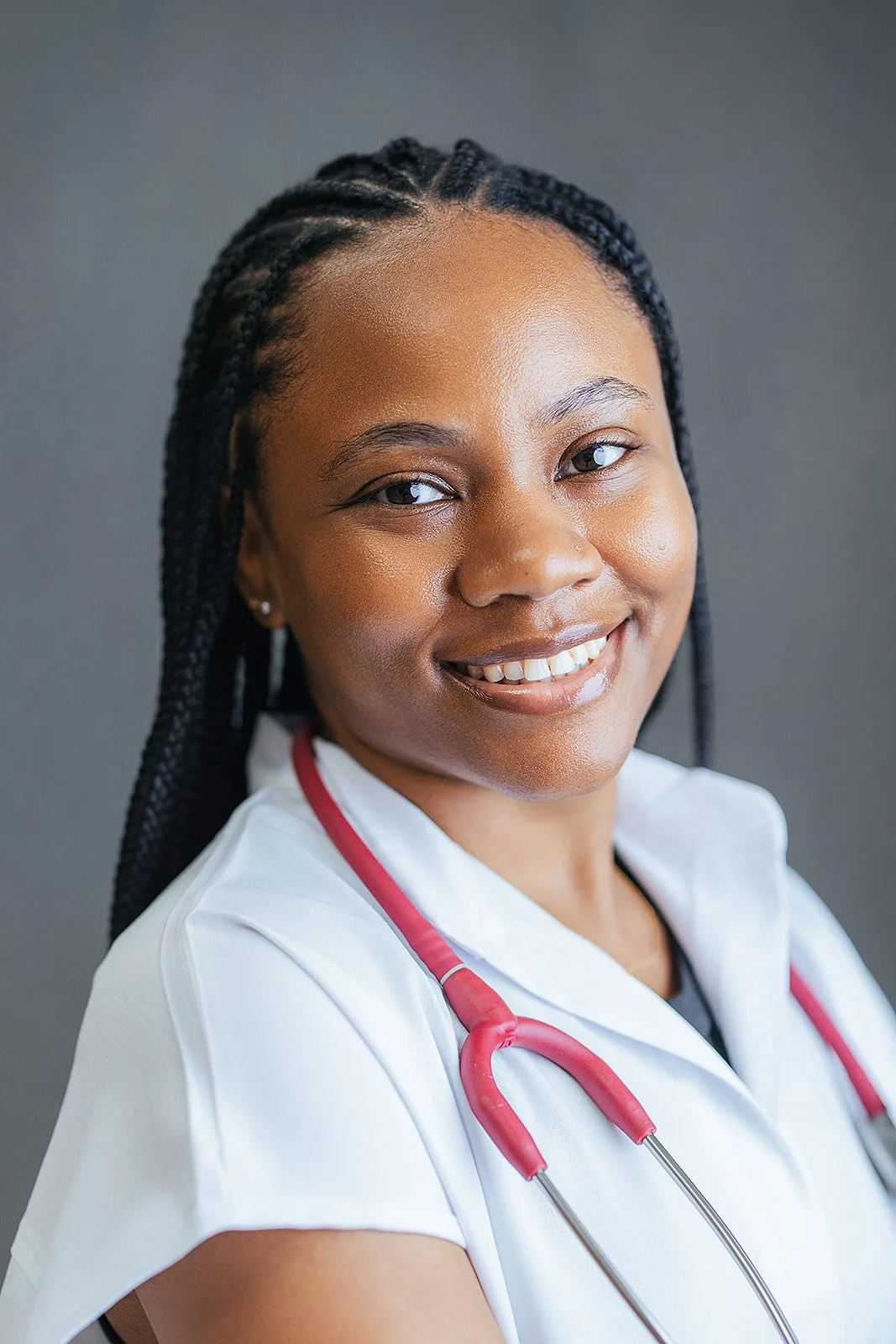 Durham Tech nursing student with long box braids, warm smile in white scrubs and red stethoscope, professional headshot in Durham NC