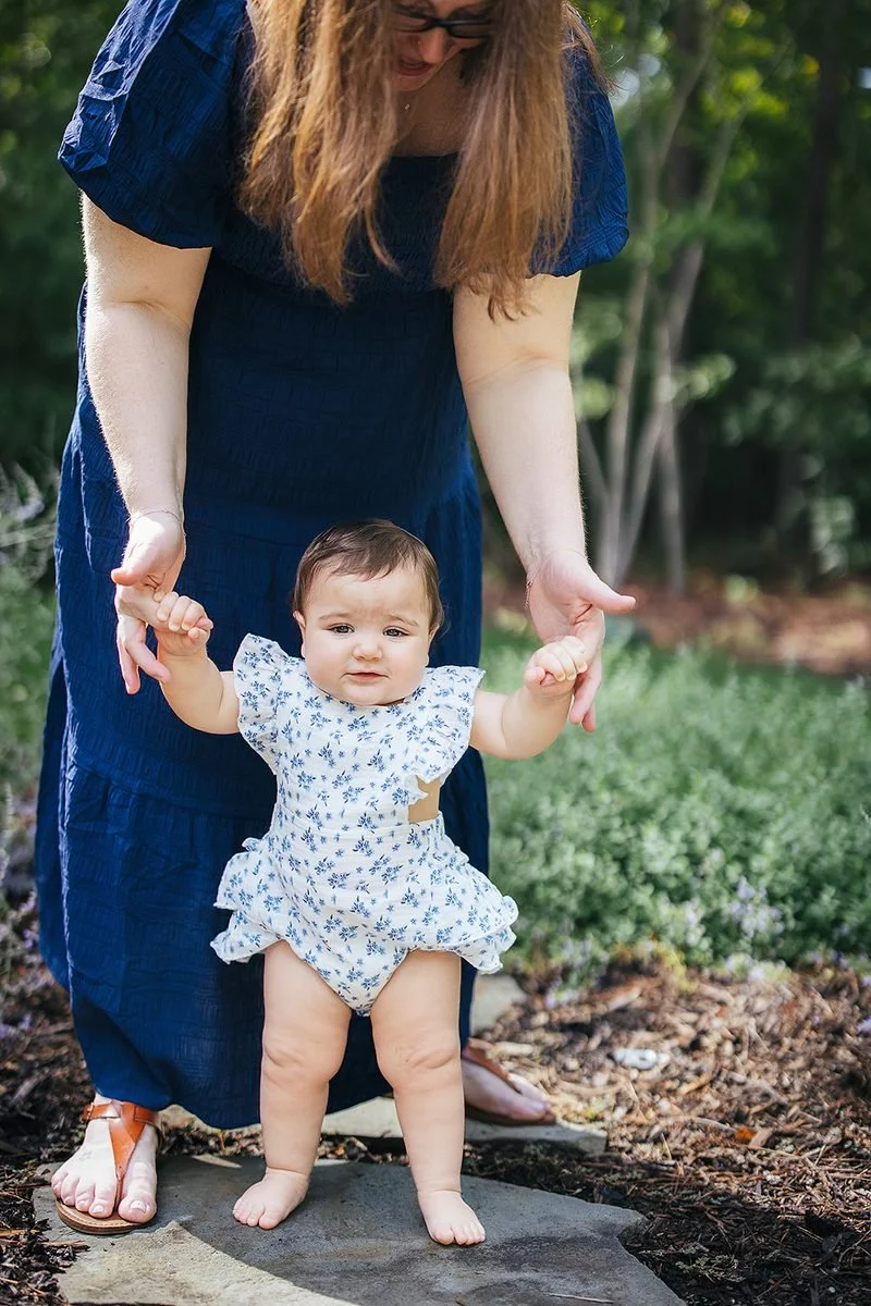 Mom holding baby's hands as she walks