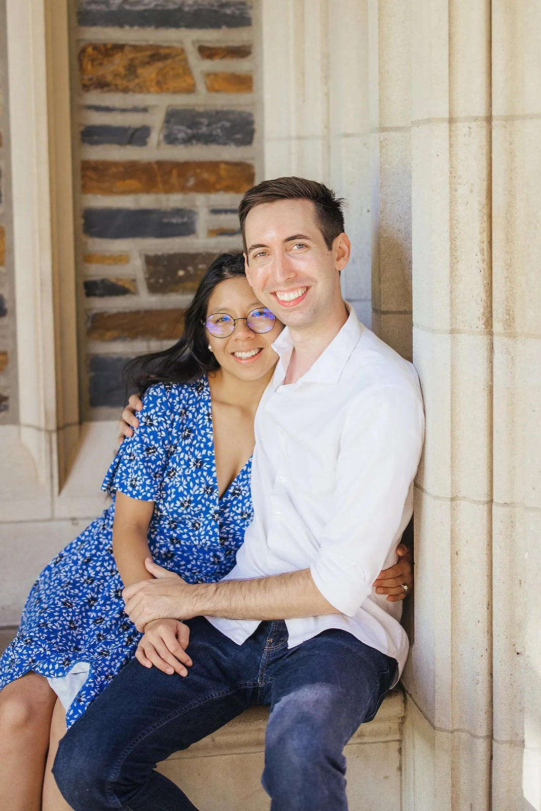 A couple smiles while seated after their surprise engagement during a photoshoot at Duke Gardens in Durham, NC
