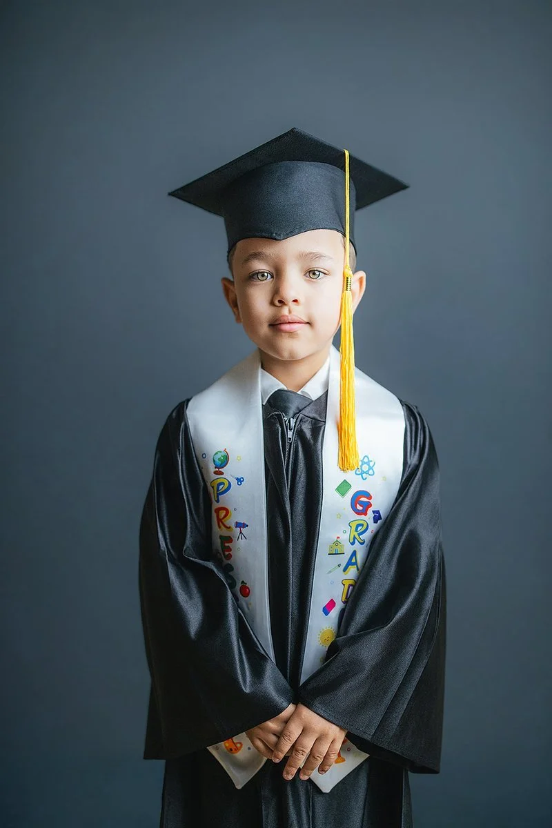 Young Boy Smiling And Standing in Preschool Graduation Robe