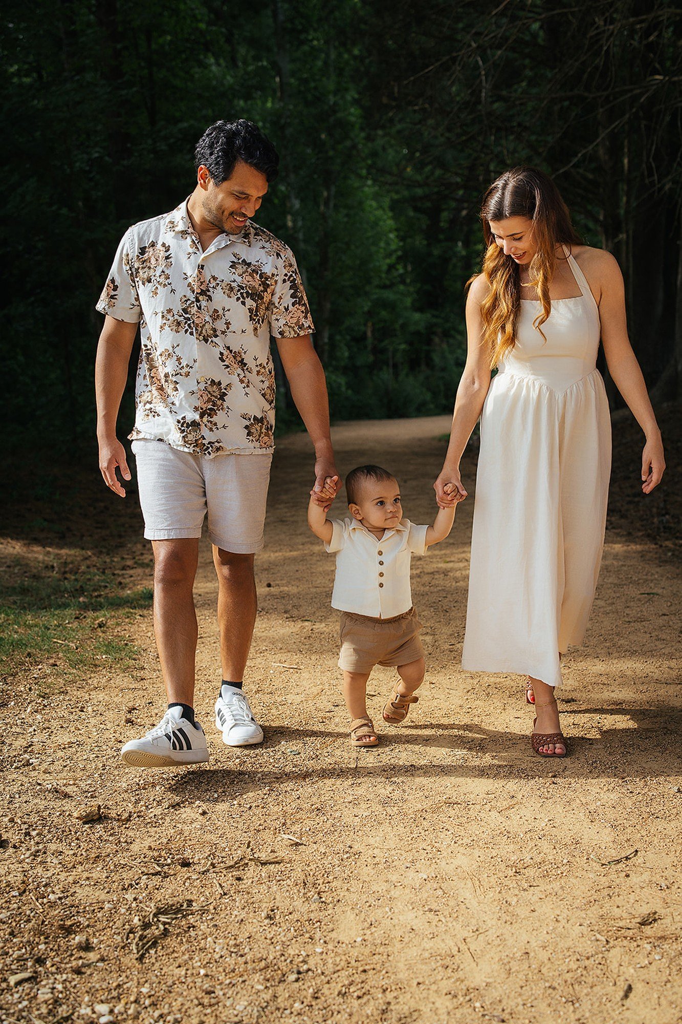 Parents Holding Young Child's Hands and Walking In Durham NC Park
