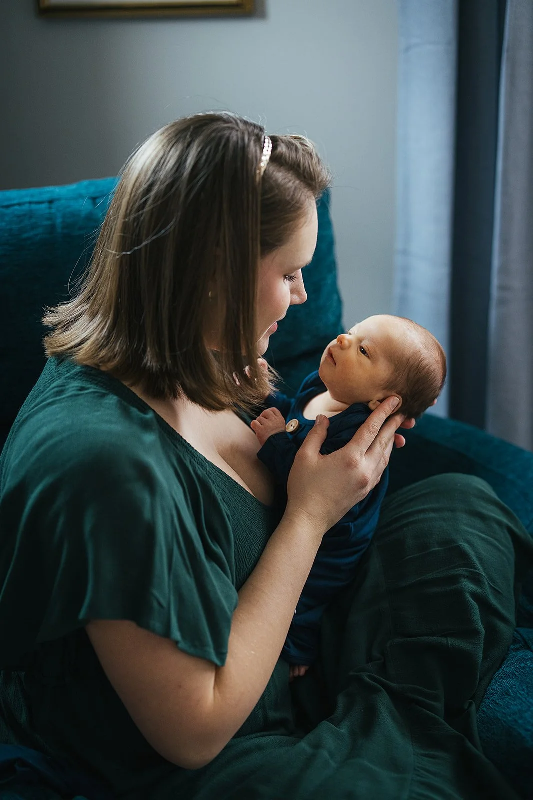 Mother wearing green dress holds baby for a newborn photoshoot in North Carolina