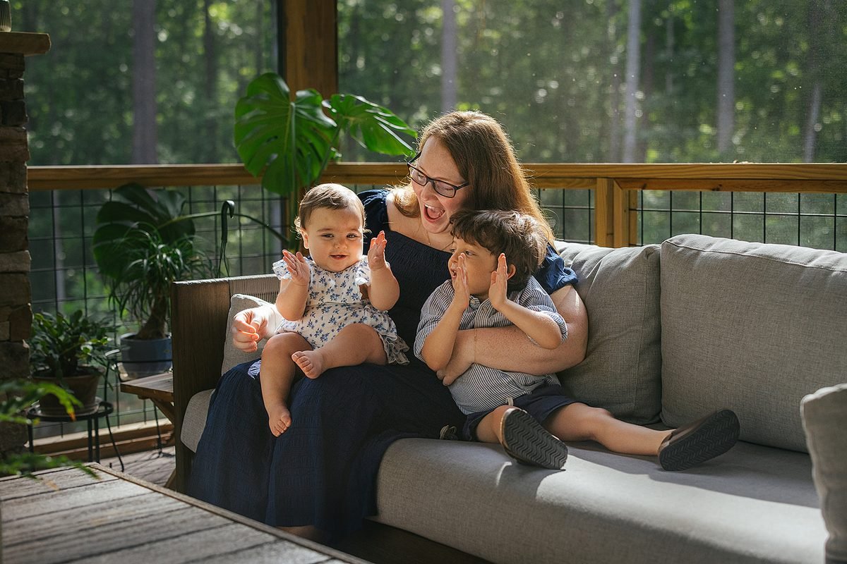 Mom sitting with two young children on back screened porch