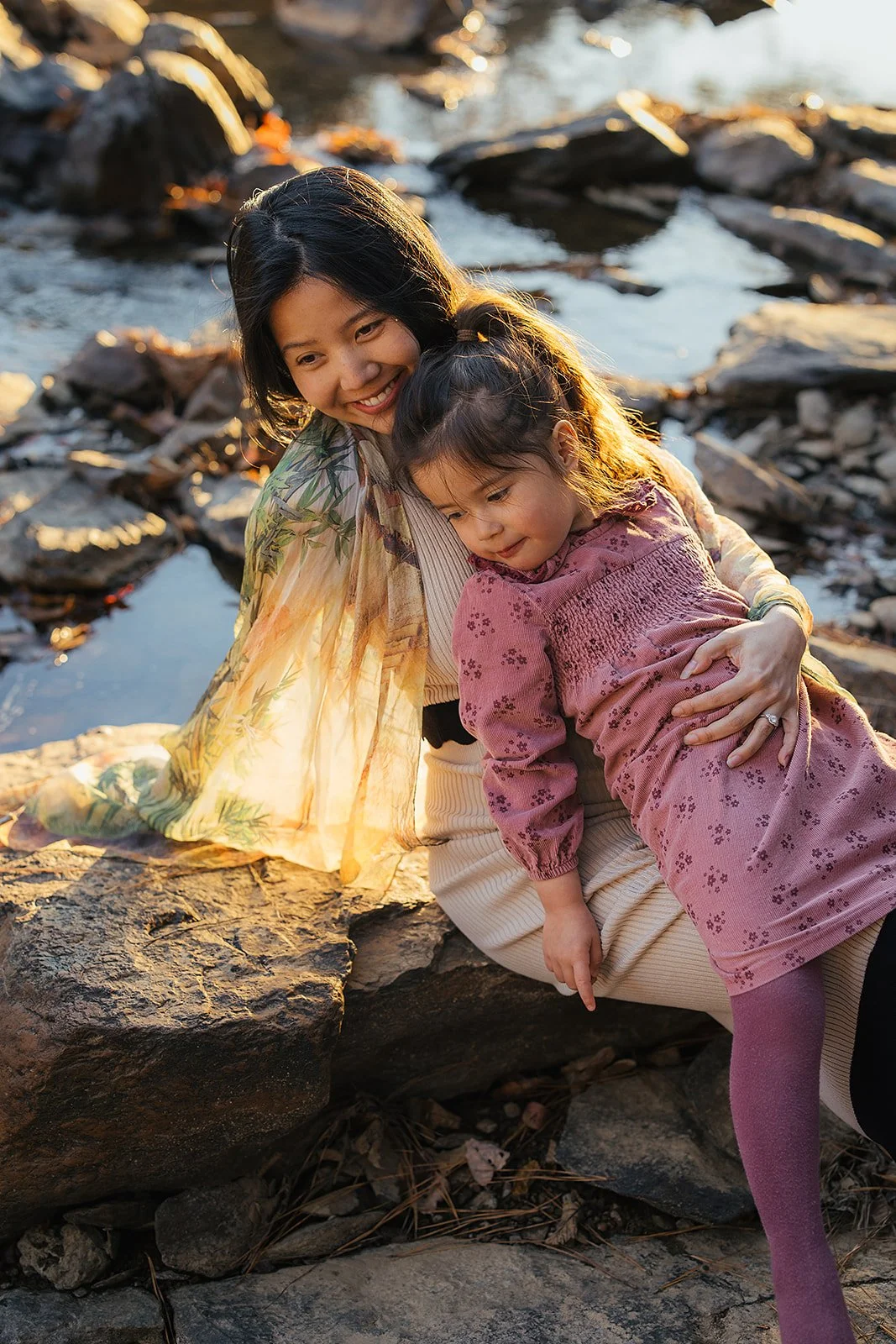 A mother and daughter pose on river rocks for a family photoshoot in Durham, NC