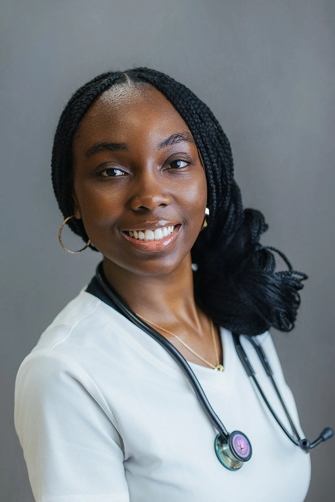 Durham Tech nursing student with long box braids, smiling in white scrubs and iridescent stethoscope, professional headshot in Durham NC