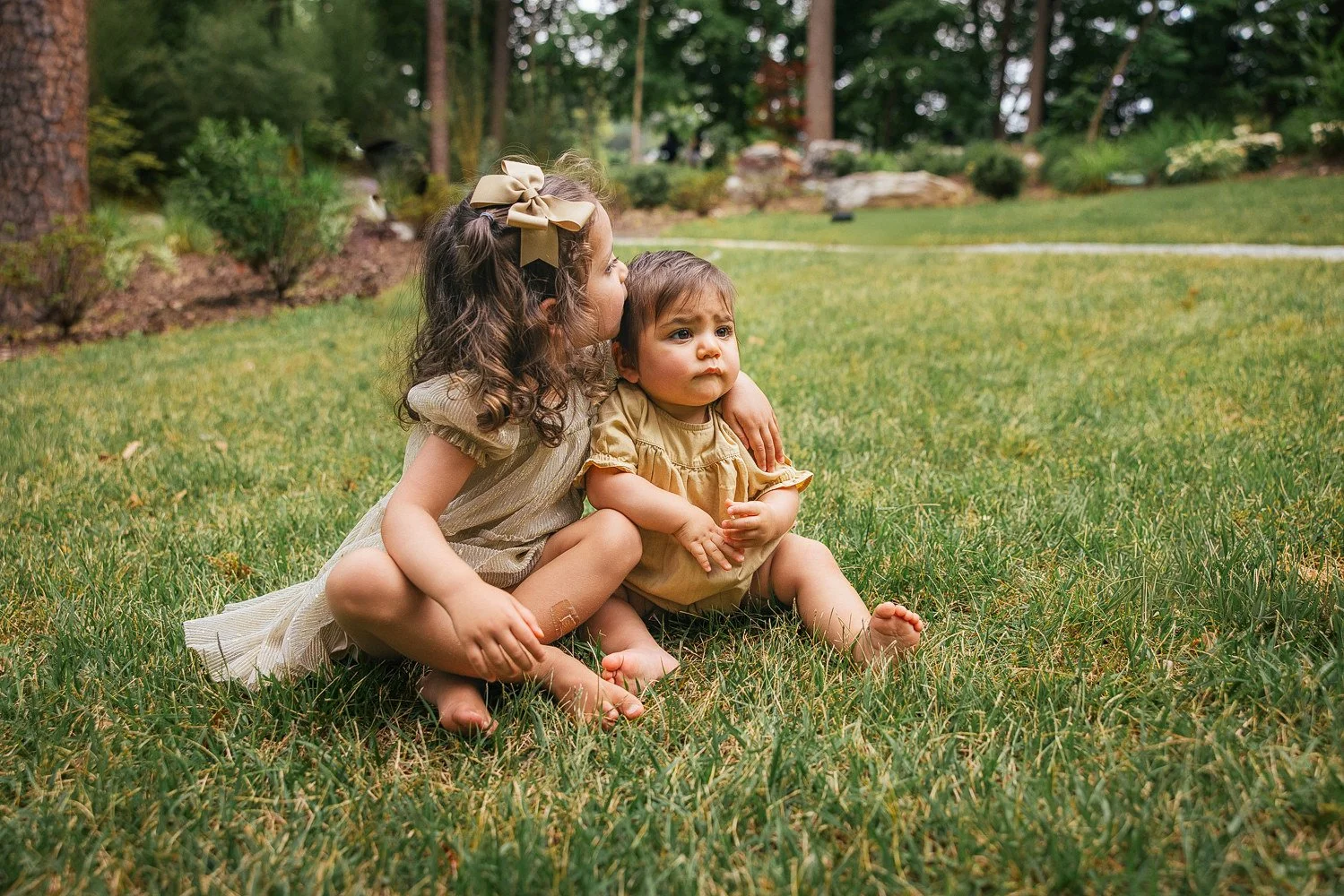 Two children snuggle on the lawn at Duke Gardens in Durham, NC for a family photoshoot