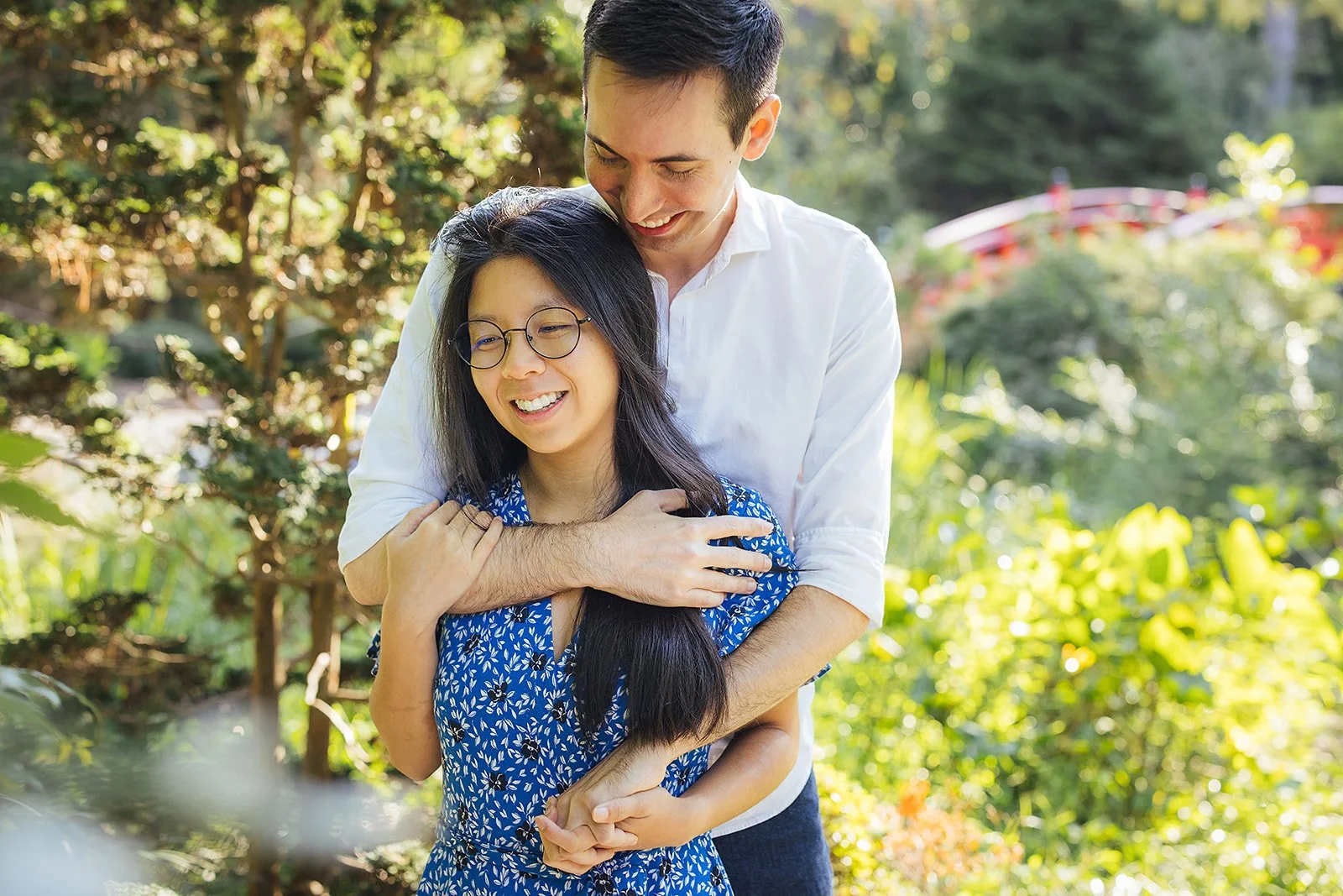 A couple hugs amid greenery after their surprise engagement during a photoshoot at Duke Gardens in Durham, NC