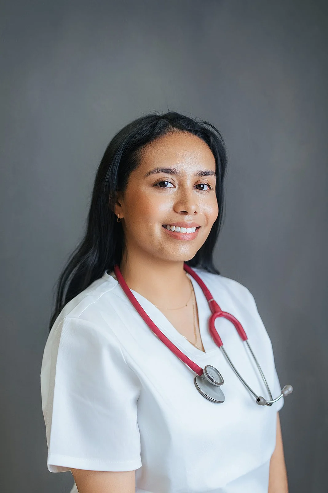 Durham Tech nursing student with long straight dark hair, gentle smile in white scrubs and red stethoscope, professional nursing headshot in Durham