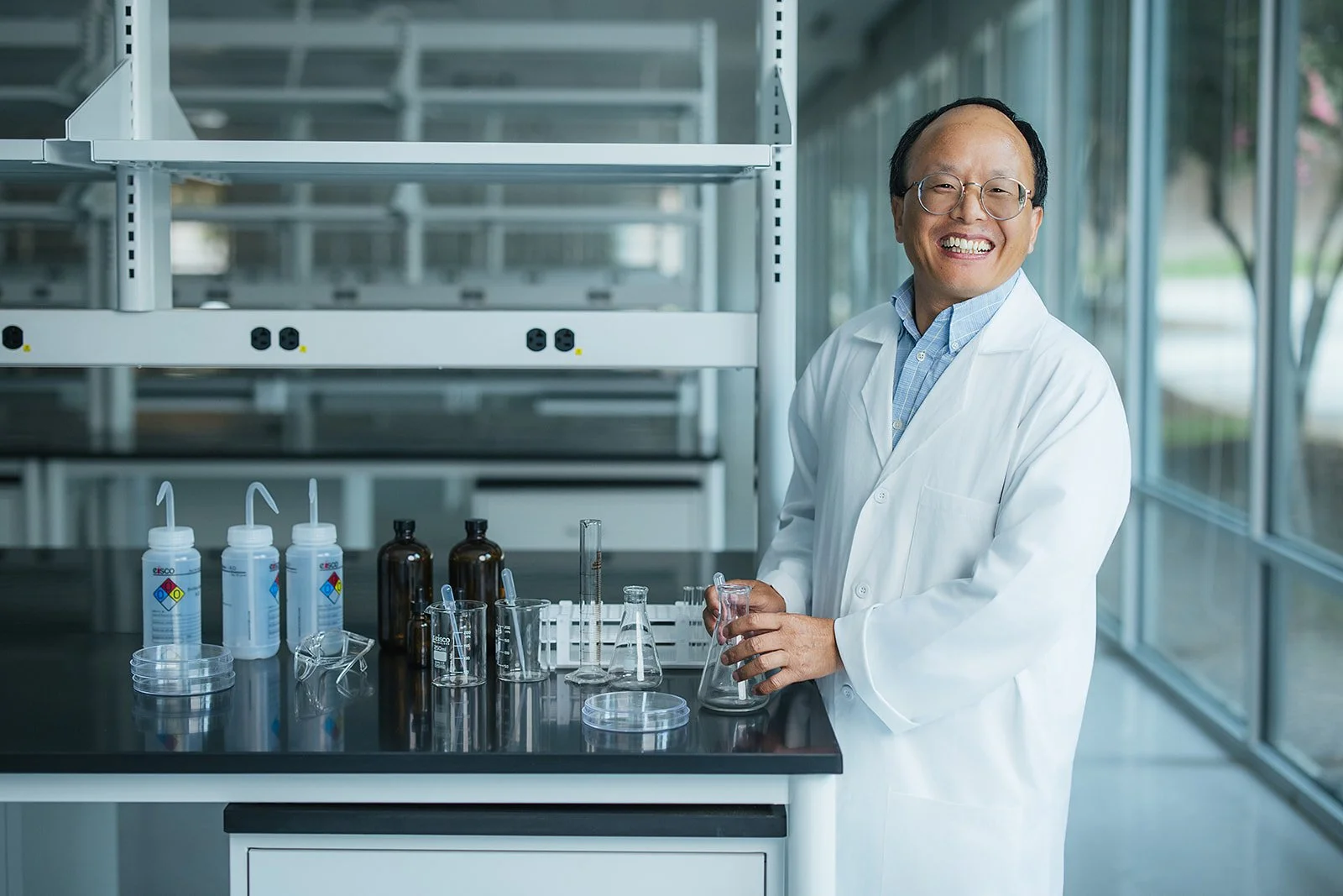 ManSmilingInWhiteLabCoatHoldingBeaker