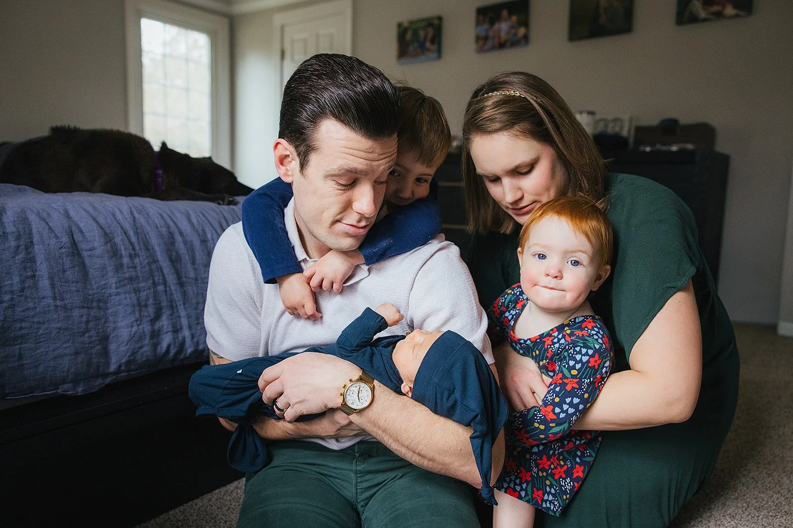 A family with three children pose in their home for a newborn family photo session in Durham, NC