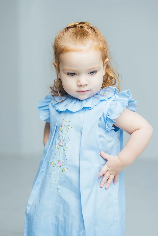 Girl with red hair and an embroidered dress poses for milestone portrait photography in Durham, NC