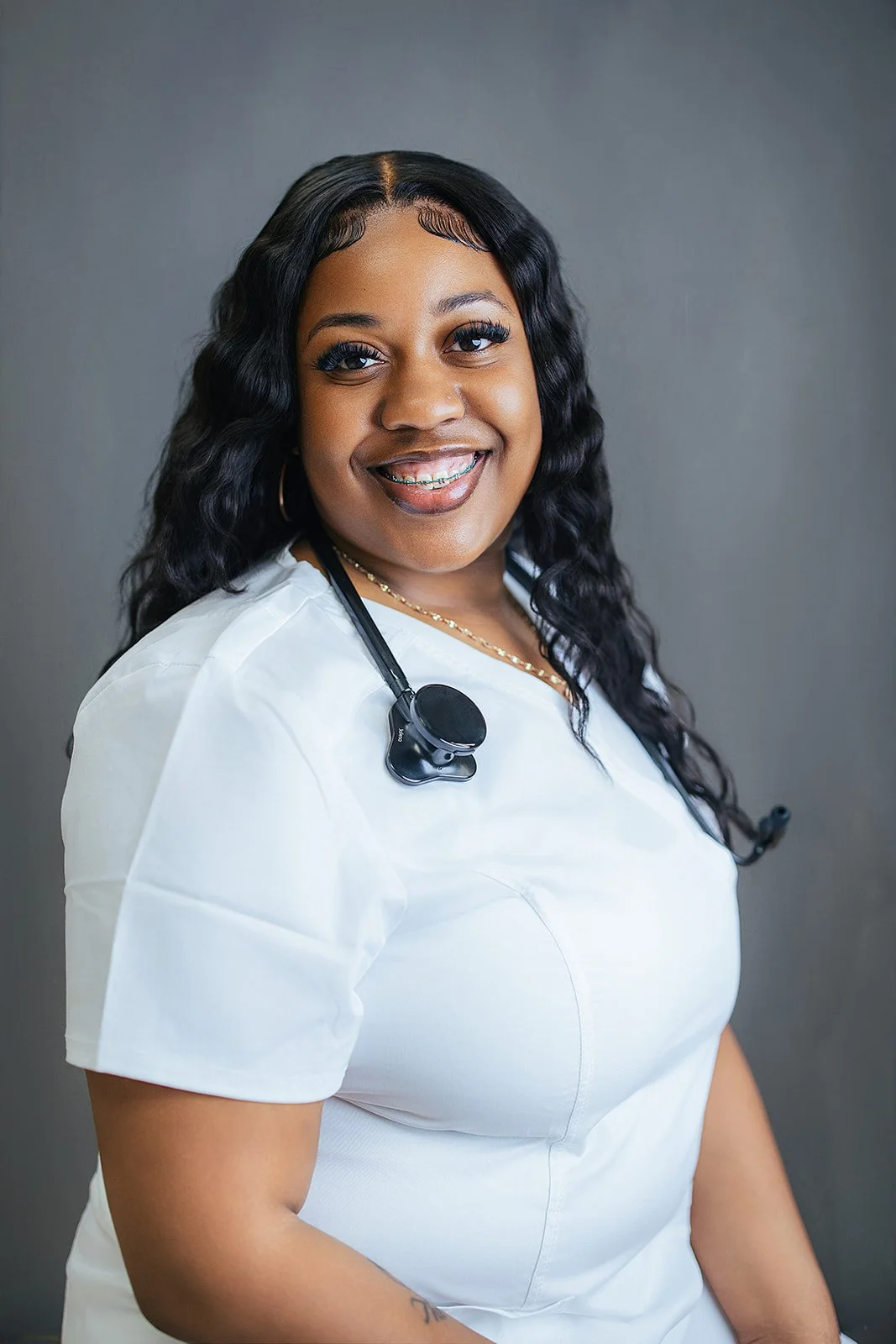 Durham Tech nursing student with long wavy hair and warm smile, wearing white scrubs with black stethoscope, professional headshot in Durham NC