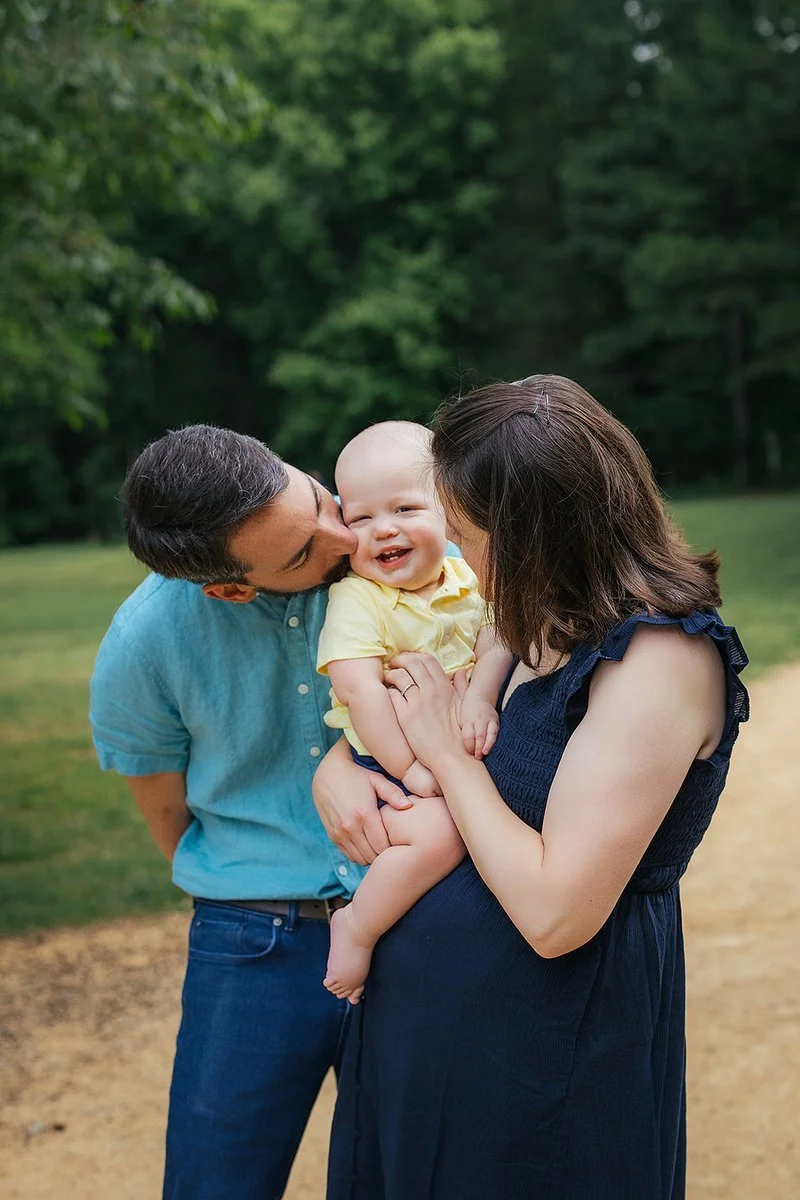 Parents Kissing Baby Cheeks in Fields at Blackwood Farm Park in Chapel Hill, North Carolina