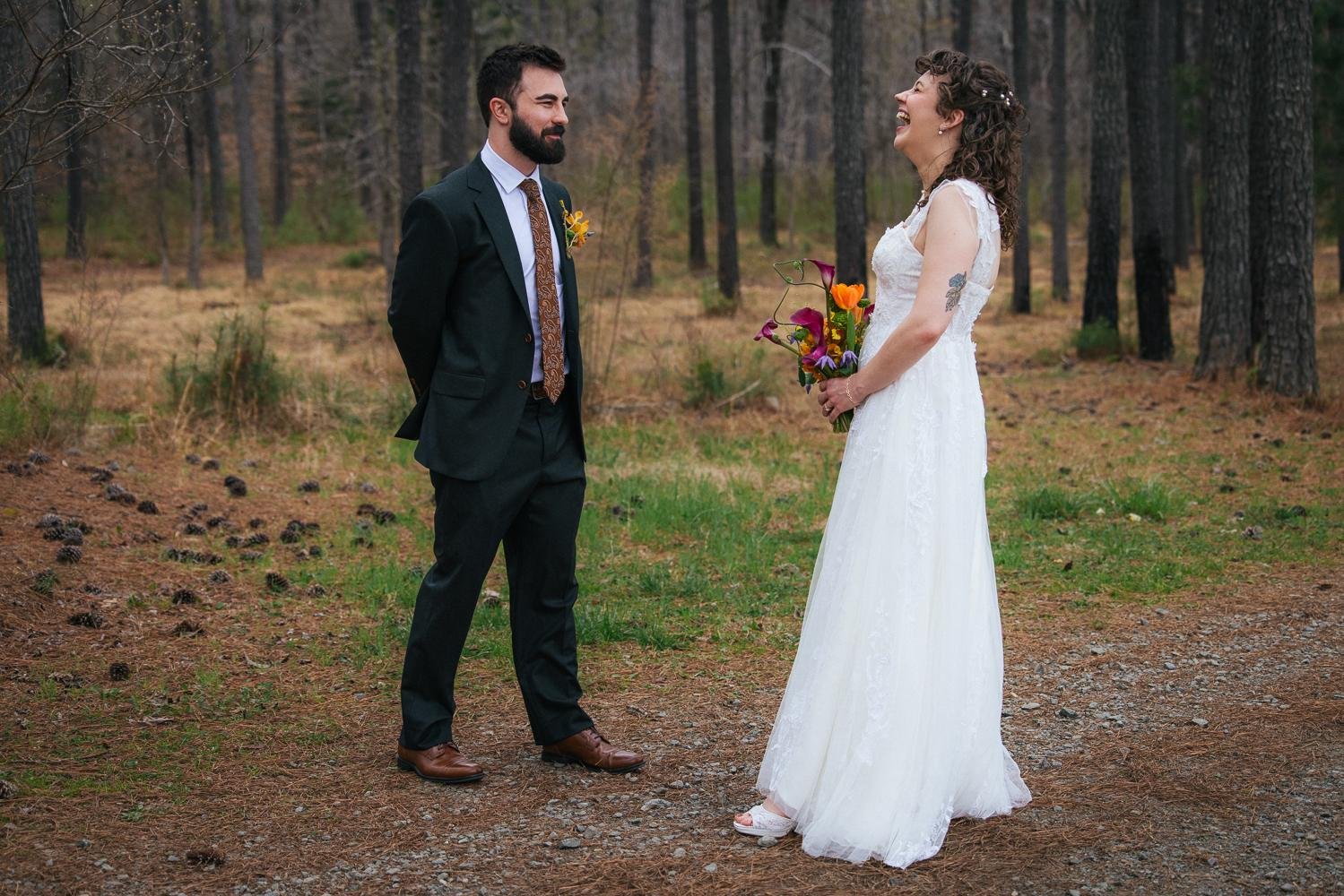 Groom seeing bride for the first time during their first look in the pine forest at Honeysuckle Tea House — bride Emily laughing with joy during Chapel Hill NC wedding