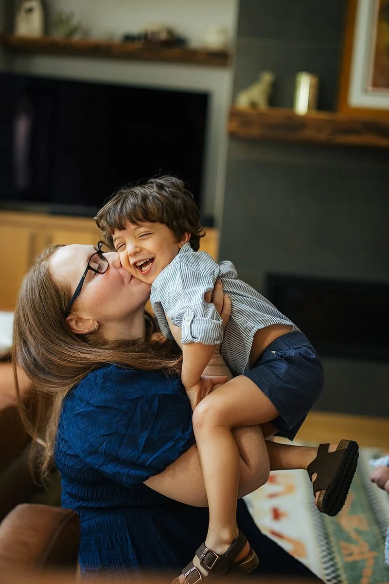Mom kissing young toddlers cheek during in-home family photography session