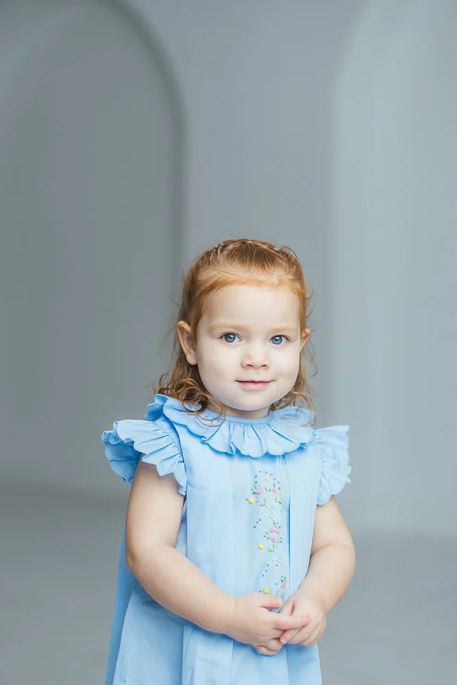 Toddler holds her hands in front of her at a studio photo session in Durham NC
