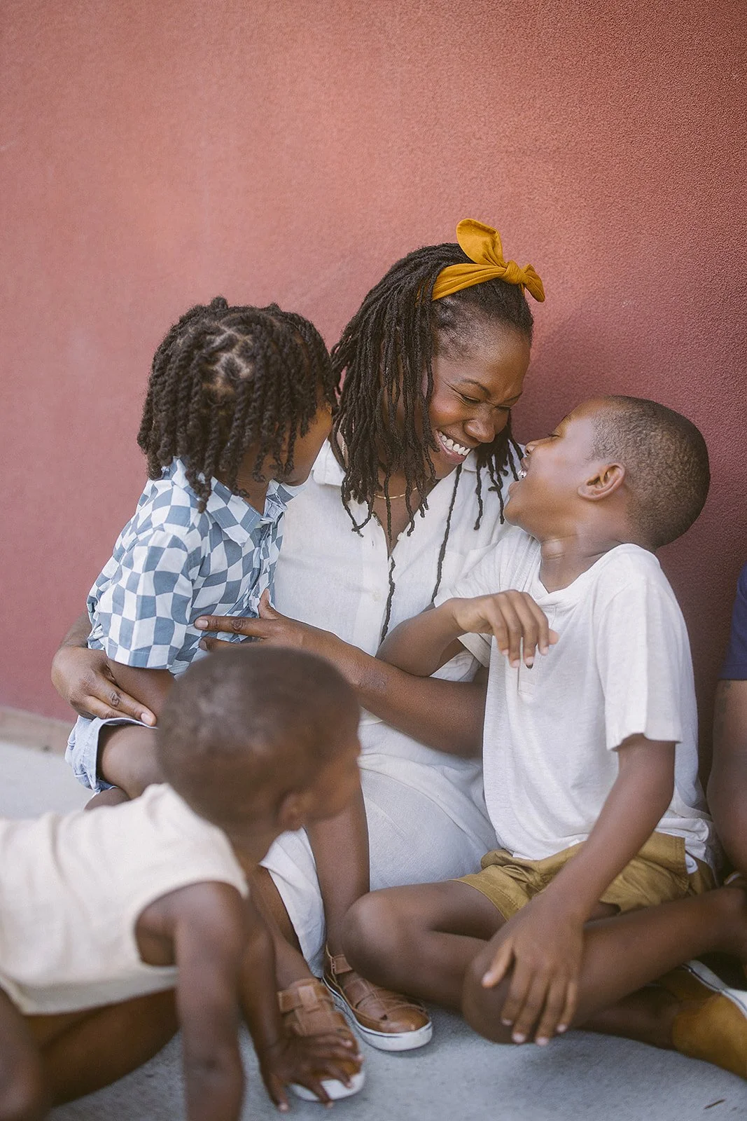 Family of four in coordinating white outfits smiles together during a Durham NC family photoshoot