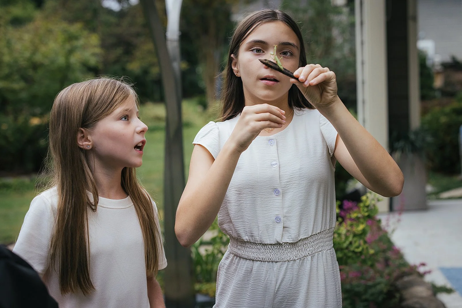 Young girls holding insect in backyard during family photography session