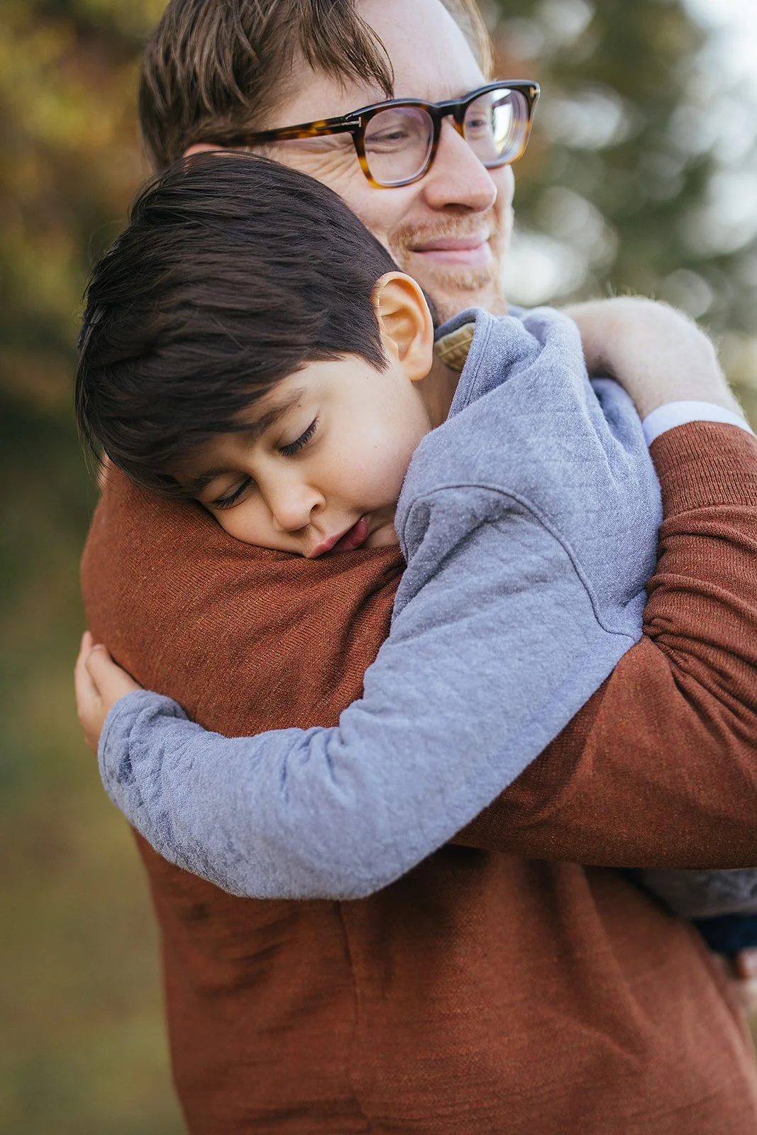 Close-up of dad hugging his young son tight at Blackwood Farm Park, son's eyes closed in a tender and emotional moment, captured by Hillsborough family photographer
