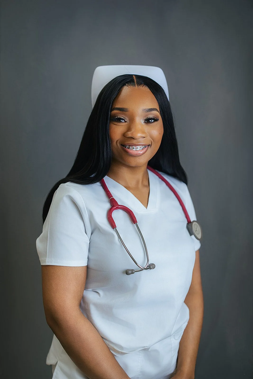 Durham Tech nursing student wearing traditional white nurse cap and red stethoscope, smiling in professional headshot by Fifty Two Hundred Photography