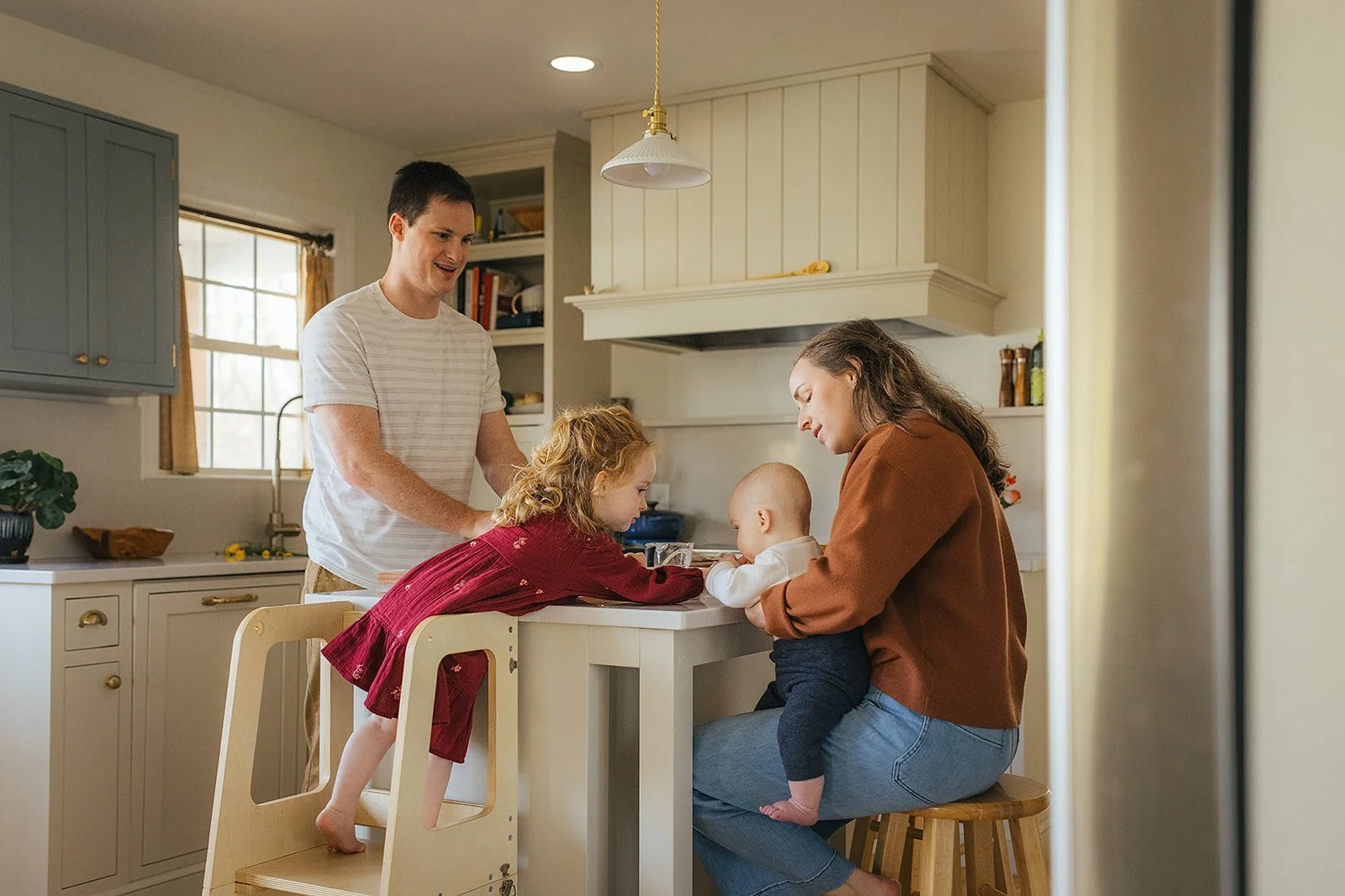 Toddler and baby share a sweet moment at kitchen island during Durham in-home lifestyle family photography session