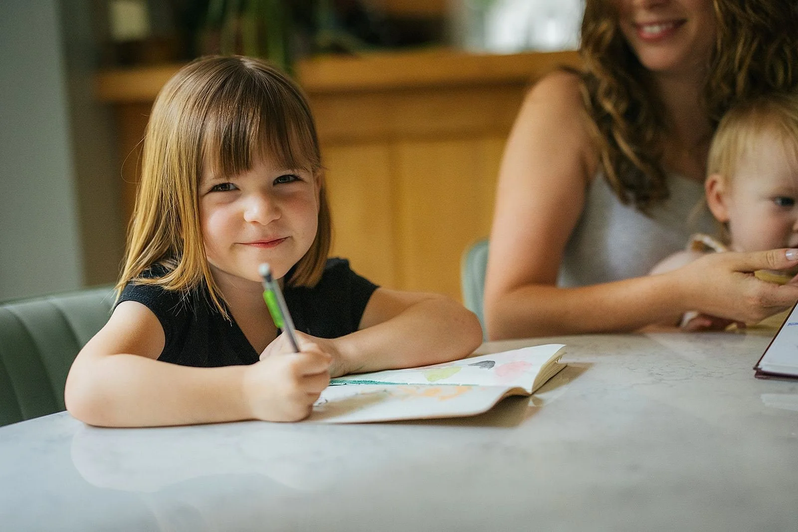 Young Girl Coloring at Kitchen Table During Durham NC In-Home Photography Session