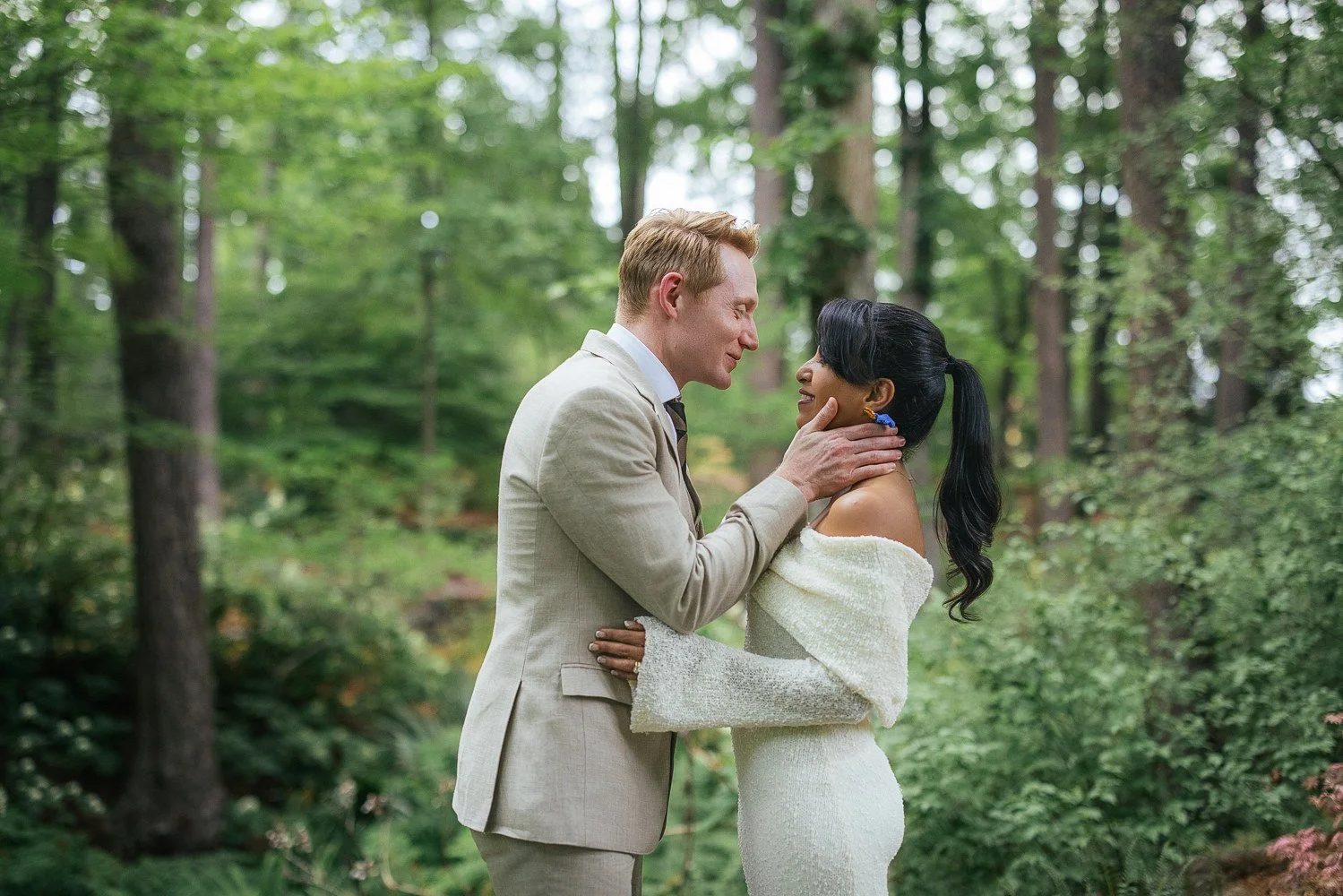 husband and wife kiss in wooded area of Duke Gardens in Durham, NC