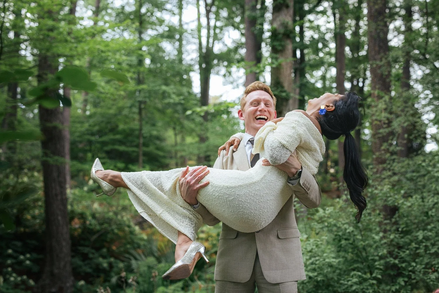 Couple smiles and laughs as groom carries bride after a vow renewal in Duke Gardens in Durham, NC