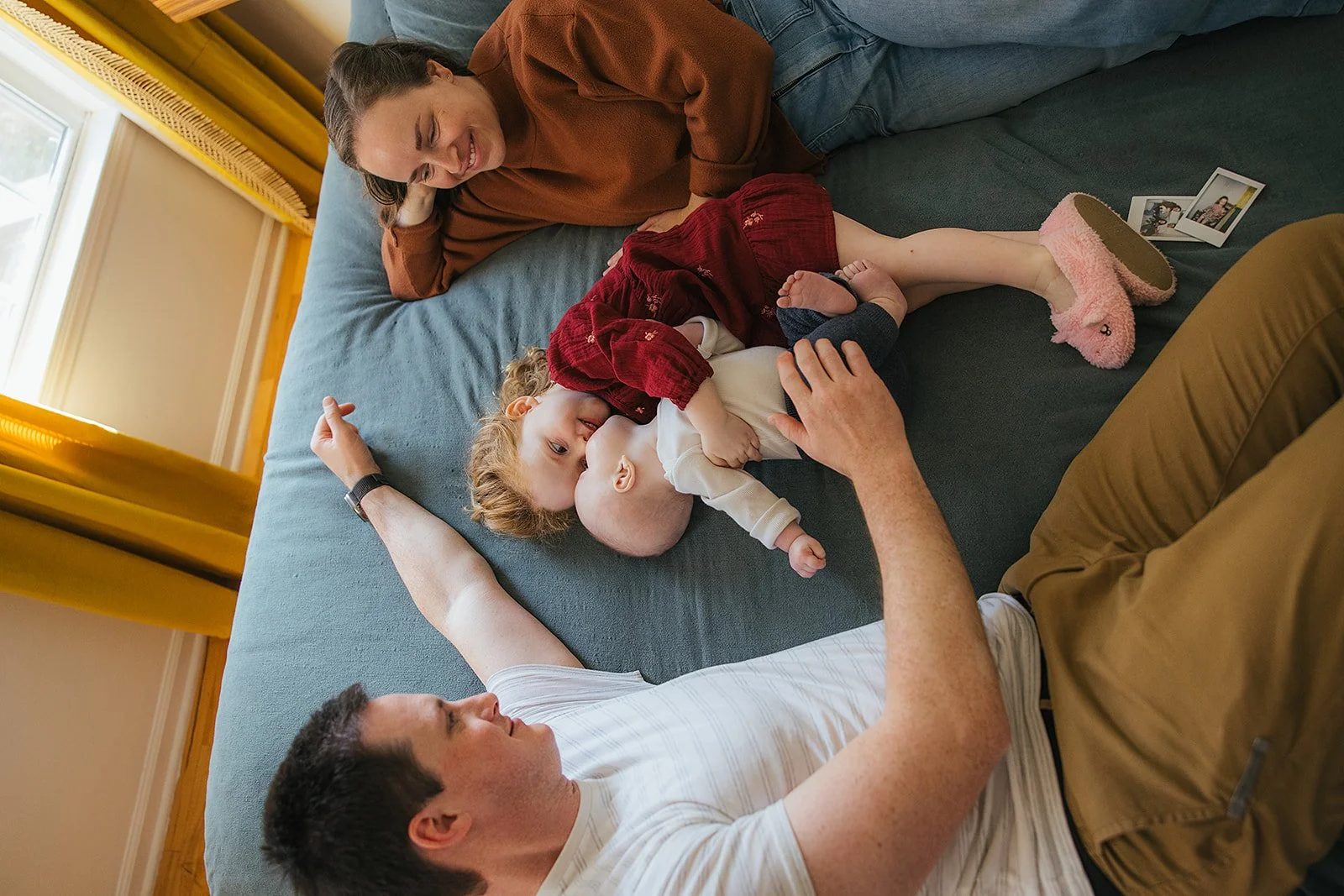 Overhead view of family of four relaxing together on bed during Durham lifestyle family photo session