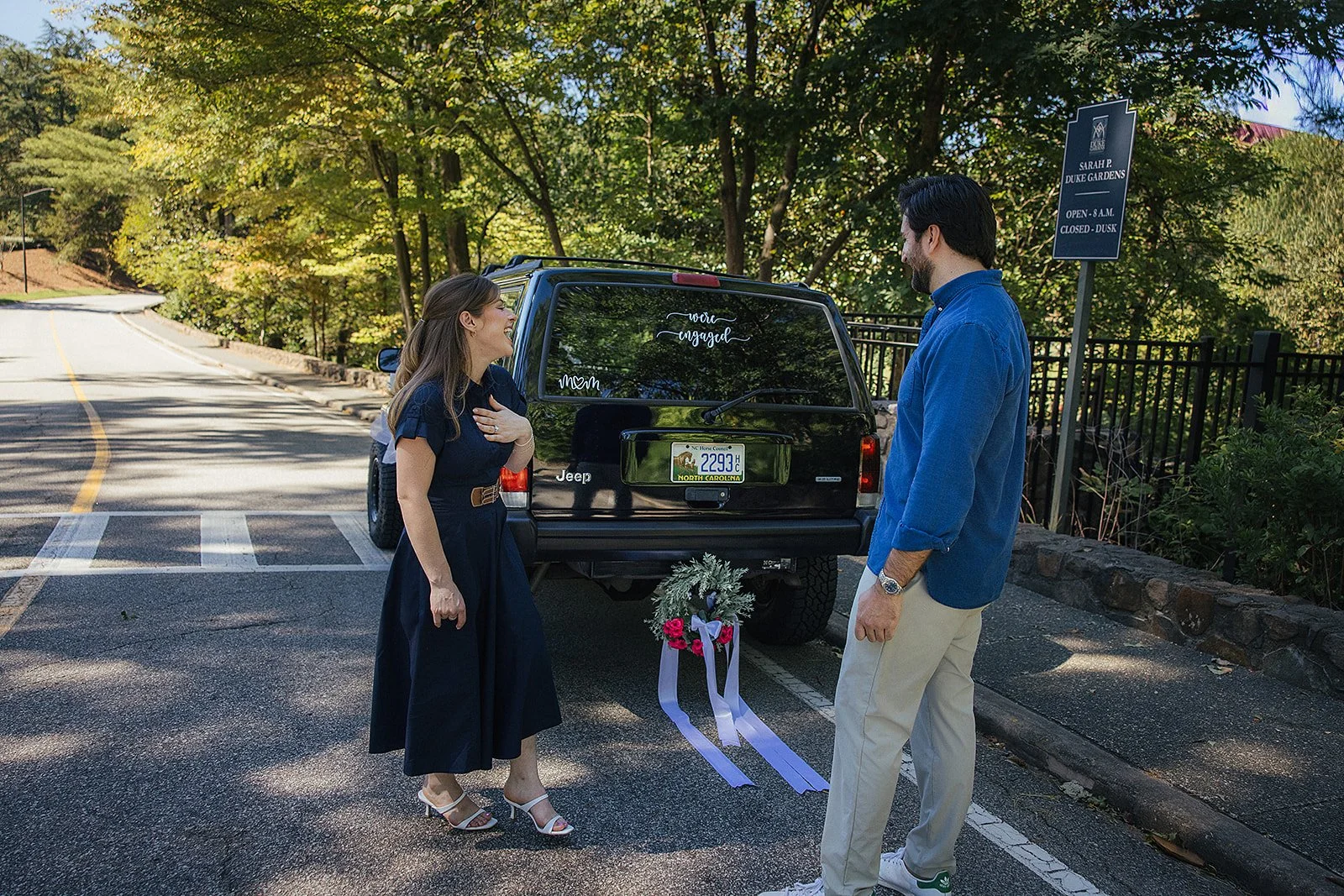 Engaged Couple smiling with a car decked out with I'm Engaged