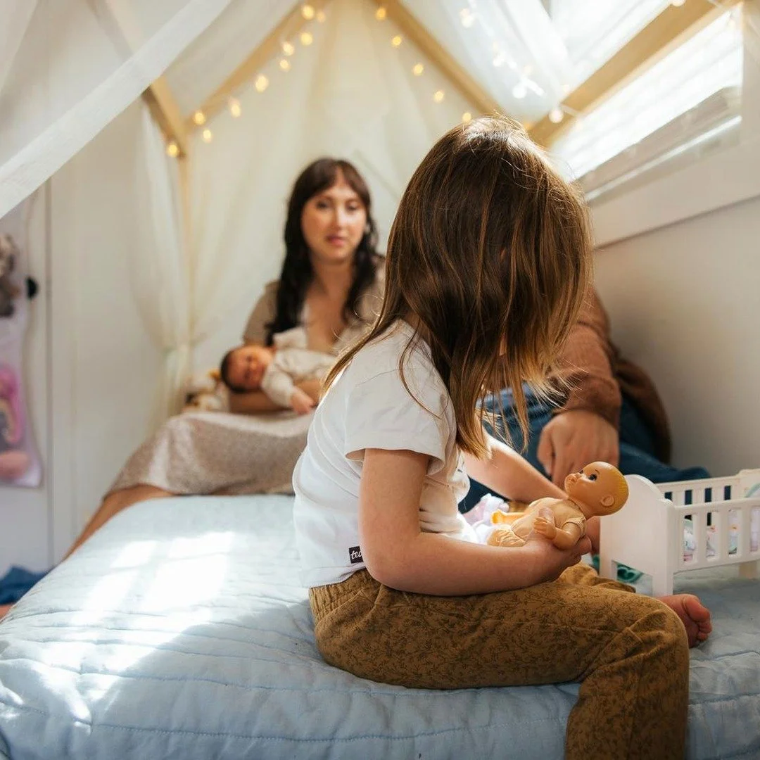 Family sits in a child's bedroom with string lights during an in home photoshoot in Durham NC