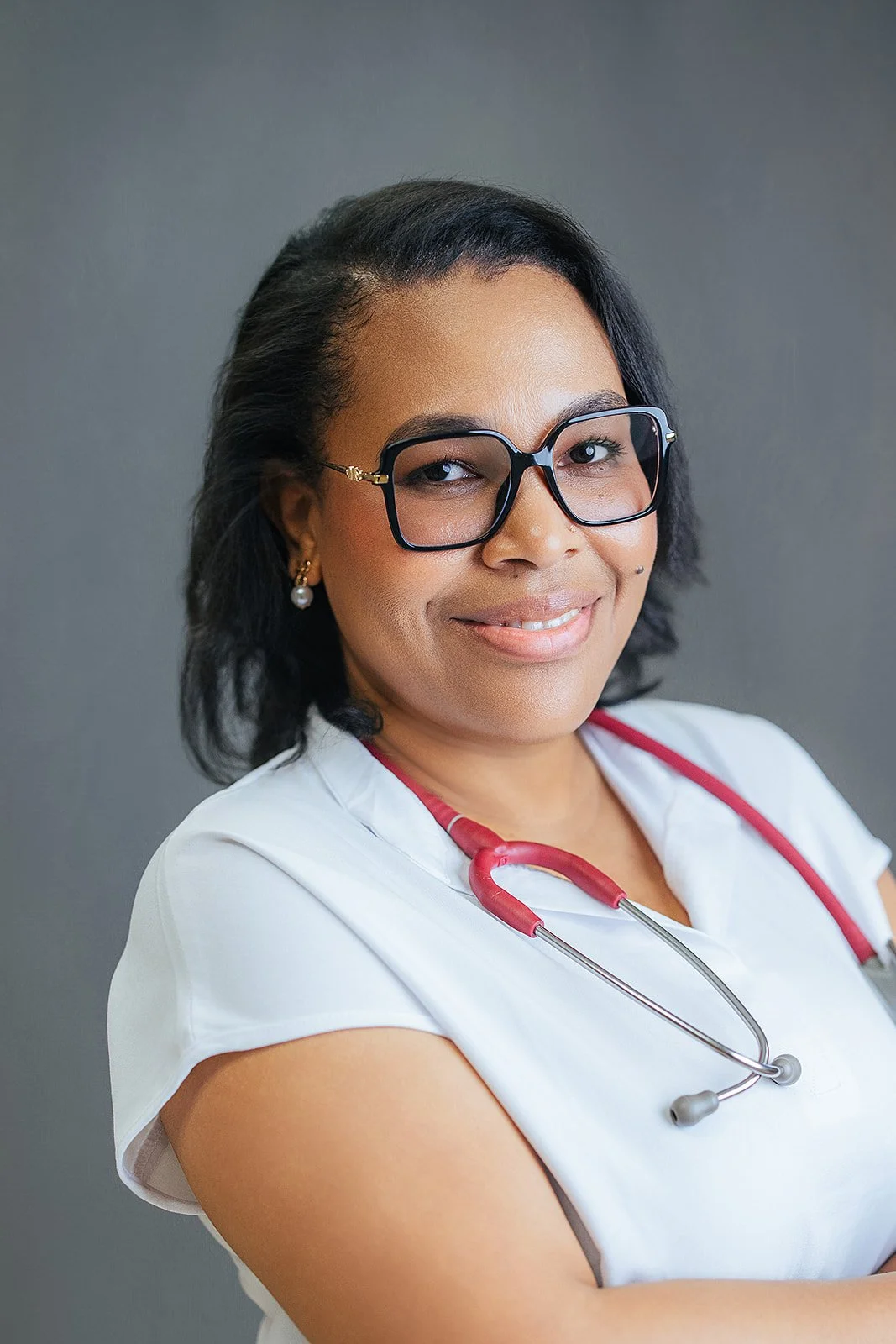 Durham Tech nursing student wearing glasses, arms crossed confidently in white scrubs and red stethoscope, professional headshot by Fifty Two Hundred Photography